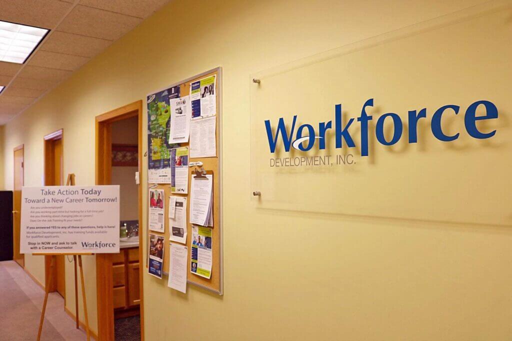 Hallway with “Workforce Development, Inc.” sign and bulletin boards featuring job and event postings at a Workforce Development Center Minnesota.
