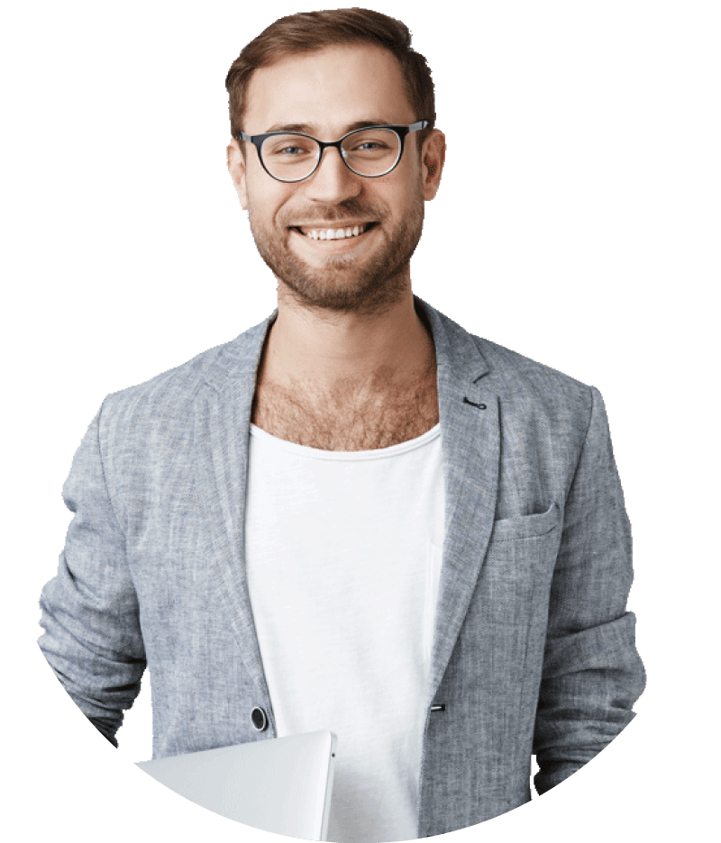 Smiling man with glasses in a gray blazer and white shirt, holding a closed laptop.