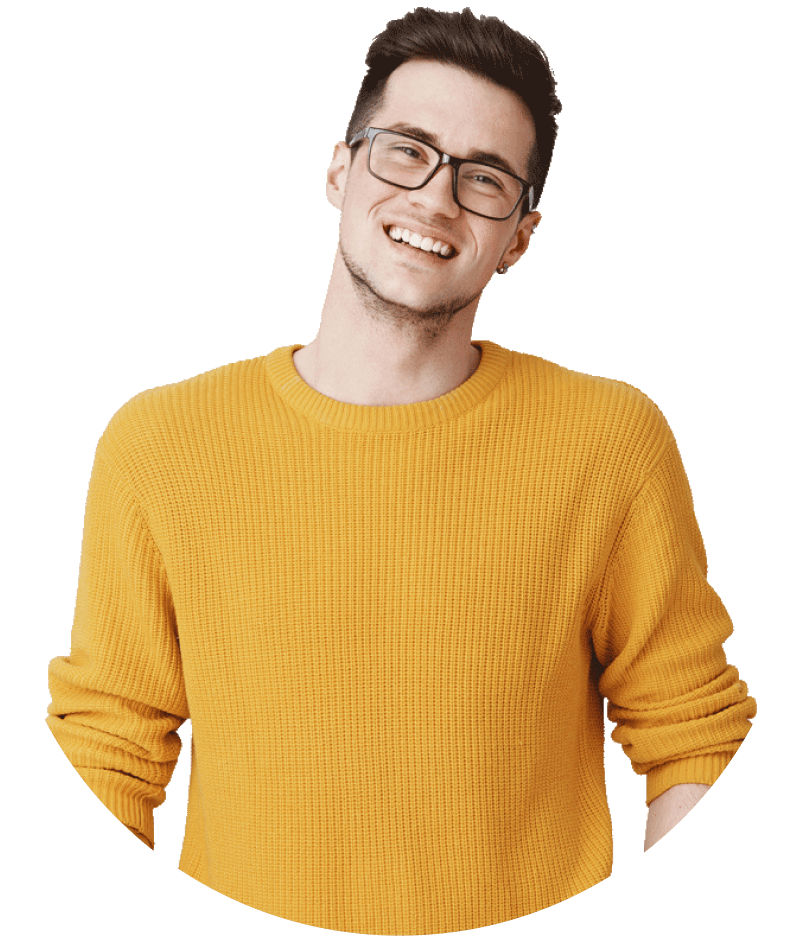 Smiling young man with glasses wearing a mustard yellow sweater against a plain white background.