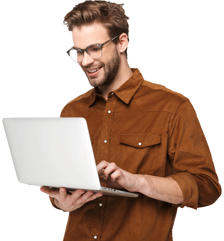 Smiling man in glasses and a brown shirt holding and typing on a laptop against a white background.