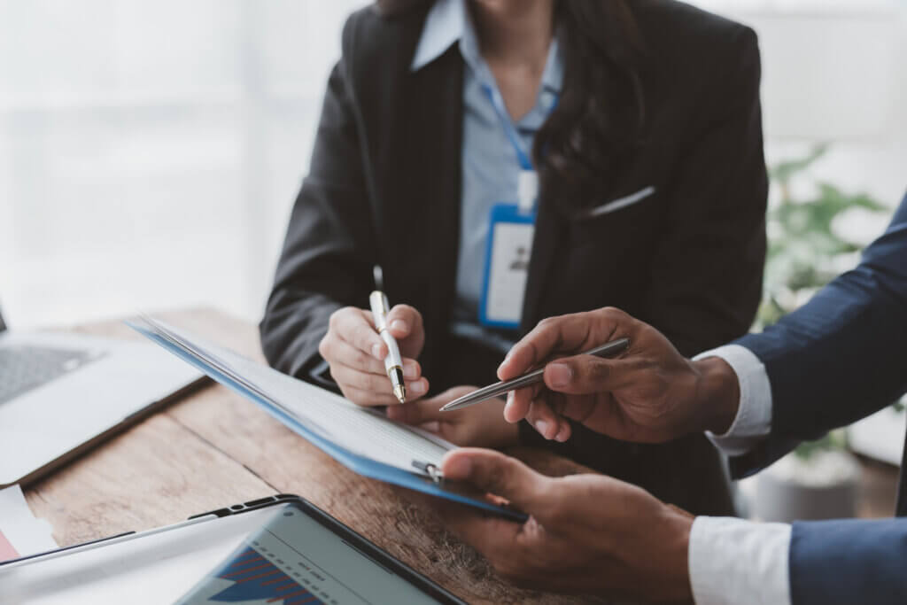 Two business professionals discussing labor market information at a desk, holding pens and a clipboard.