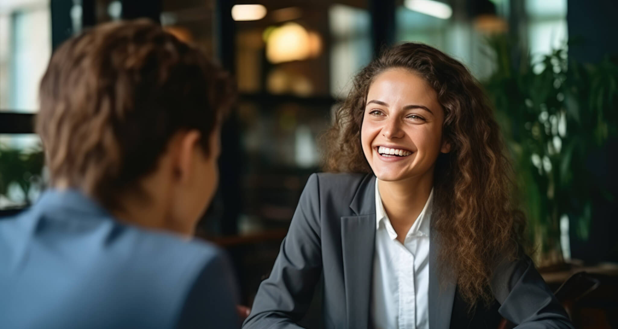 Two people in business attire smiling and discussing labor market information in a modern office setting.
